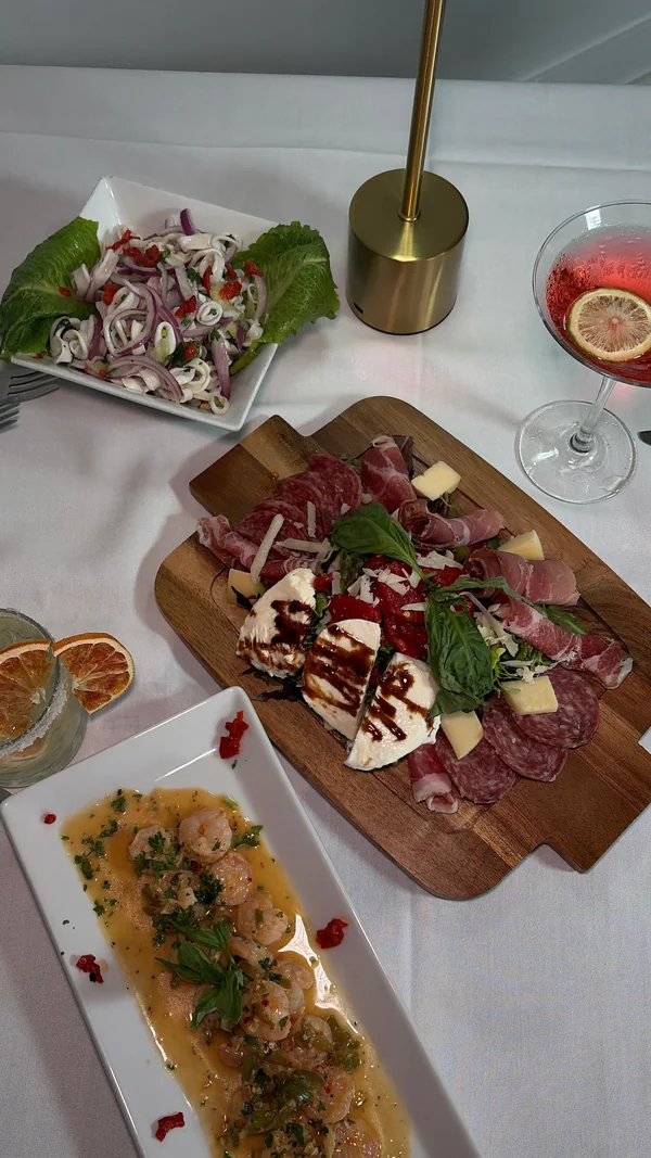 An antipasti board with meat, cheese and roasted peppers, alongside shrimp and calamari salad at Olive & Oak