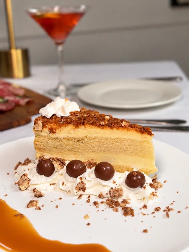 Layered cream cake with chocolate, whipped cream and caramel on a white plate at Olive & Oak