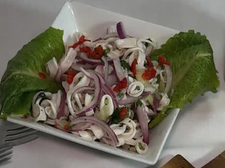 Olive & Oak's calamari salad with red onion and greens on a white plate